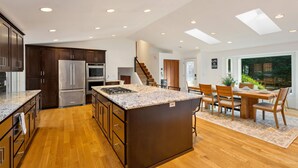 Una cocina moderna con una isla central, electrodomésticos integrados y un comedor con vistas.