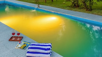 Relax by the serene pool surrounded by lush greenery and trees, perfect for a tranquil retreat.