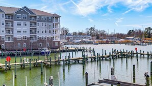A marina with docked boats, a building with balconies, and a clear sky. - Walk to Dtwn: Waterfront Eastern Shore Townhome! (Cambridge)