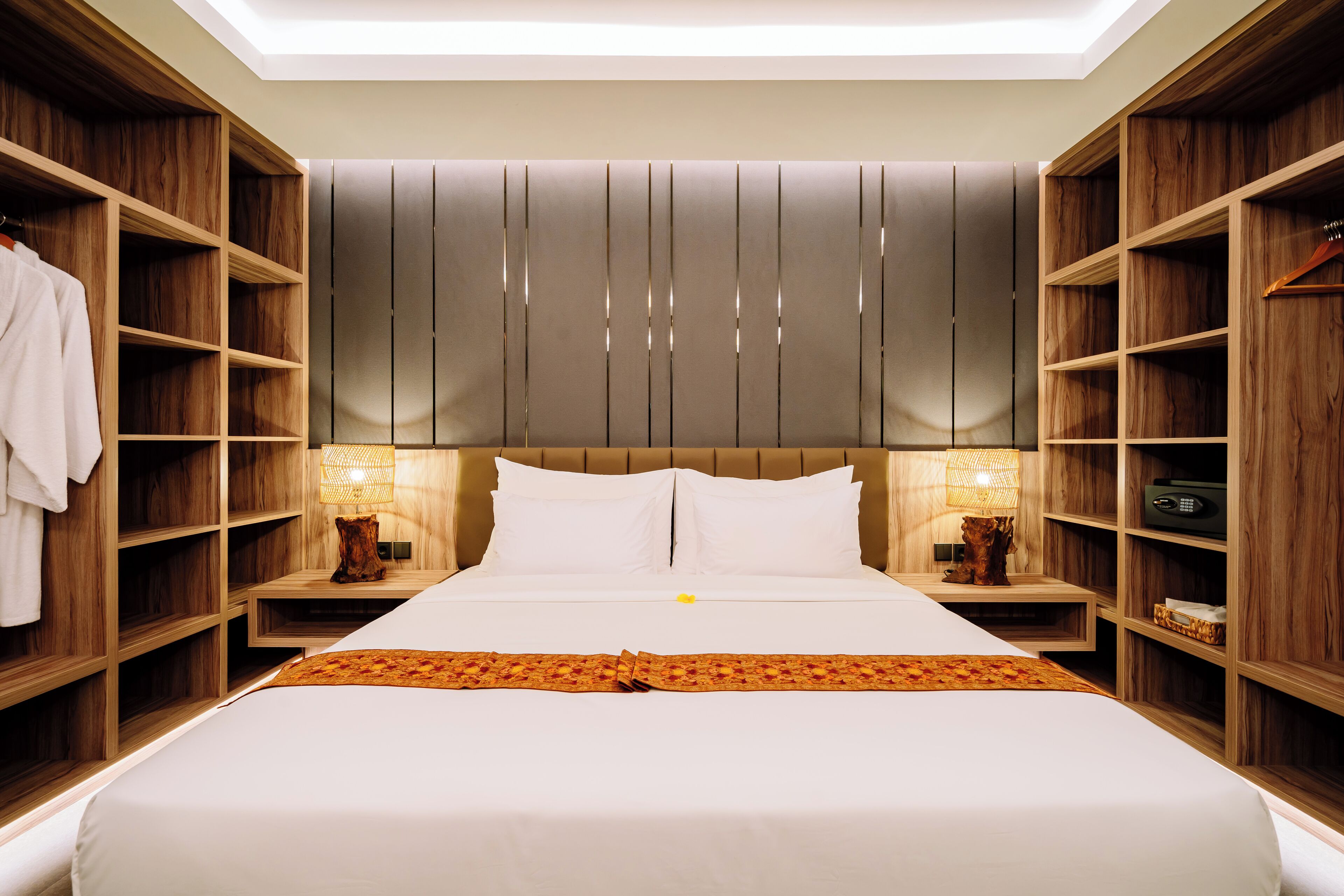 Une chambre d’hôtel moderne avec un grand lit, des étagères en bois et un luminaire au plafond.