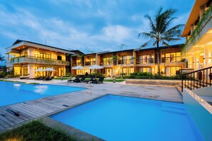 A modern hotel with a swimming pool, sun loungers, and a well-lit outdoor area. - Big Dragon Villas Ubud (Ubud)