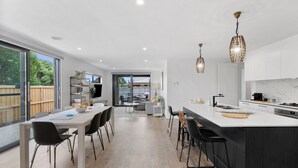 A modern kitchen with a large island, bar stools, and pendant lighting. - Adelphi Family Home Near Queenscliff Ferry 10 Min (Point Lonsdale)