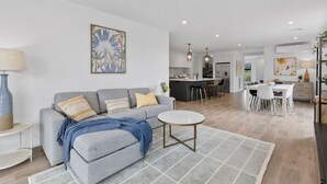 A modern living room with a grey sofa, round coffee table, and a dining area with a white table and chairs. - Adelphi Family Home Near Queenscliff Ferry 10 Min (Point Lonsdale)