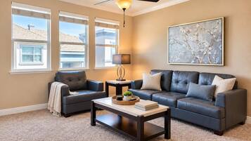 Bright living room with a plush leather sofa set, ceiling fan and big sunny windows.