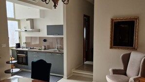 Una cocina moderna con armarios blancos, un comedor con mesa y sillas de madera, y un cuadro grande en la pared.
