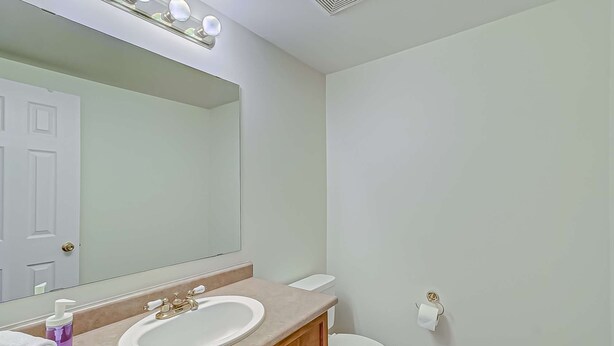 A bathroom with a white sink, vanity, and mirror. There is a toilet and a towel rack visible. - Modern & Spacious 5BR/ 4Bath (Toronto)