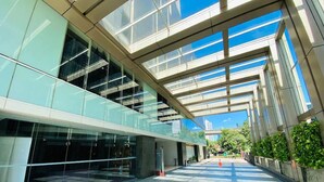 Un bâtiment moderne doté d’une façade en verre, d’une cour intérieure spacieuse et surplombant un ciel dégagé.