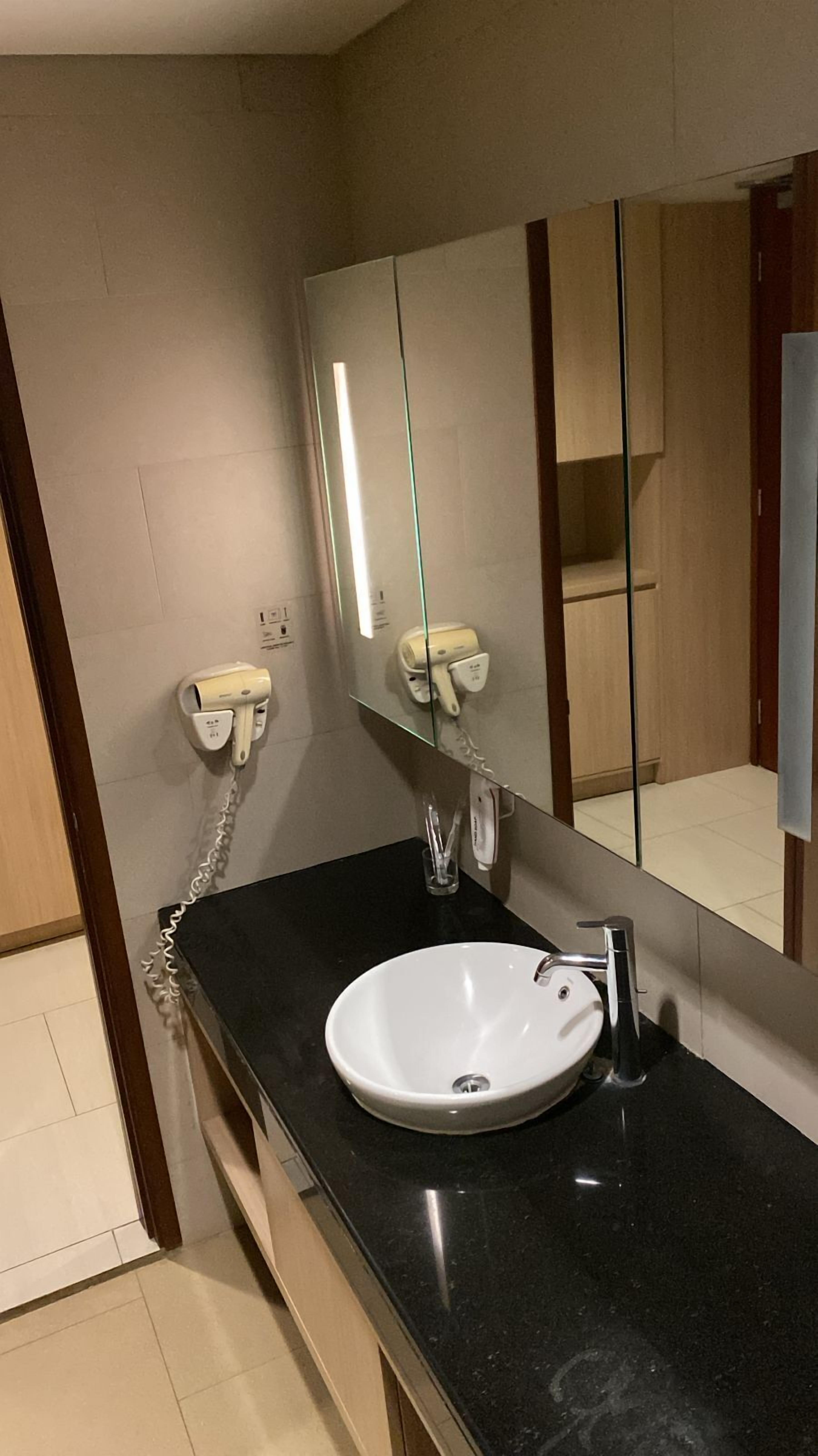 A modern bathroom with a black countertop, a white sink, and a mirror.