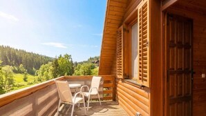 Una cabaña de madera con balcón, una mesa y dos sillas.