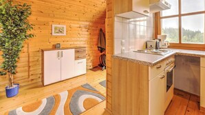 Un interior de madera con una zona de cocina, que incluye armarios, una estufa y una ventana con vistas.