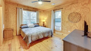 Una habitación con paneles de madera, una cama, un escritorio y un ventilador de techo.