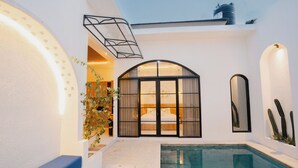 A pool area with a glass enclosure, a bench, and cacti on the wall.