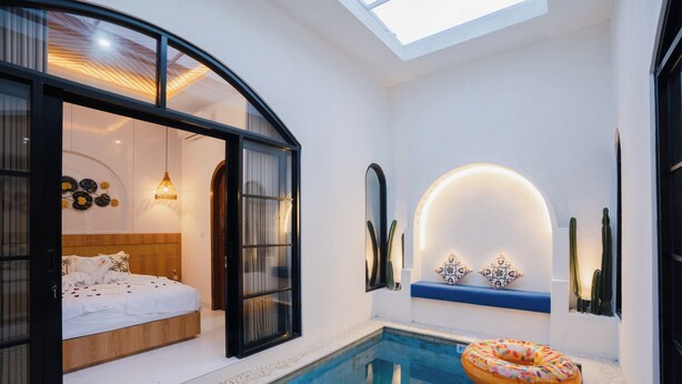 A modern bedroom with a built-in pool, a floating ring light, and a skylight.