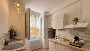 A modern kitchen with a marble countertop, wooden cabinets, and a built-in stove.