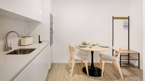 Cocina compacta con lavamanos, tostadora y una pequeña mesa de comedor con sillas.
