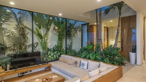 A modern living room with a large flat-screen TV, a beige sofa, and a wooden coffee table.