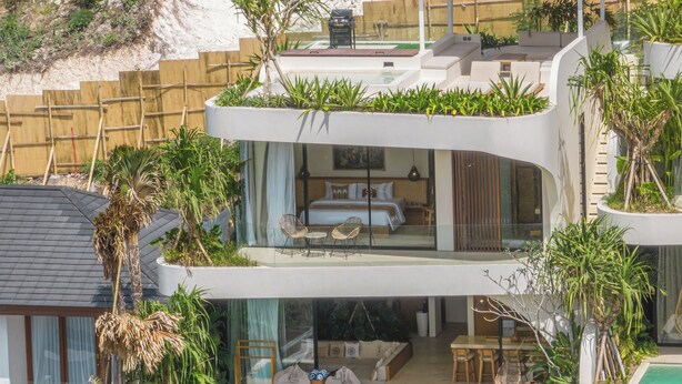 A modern multi-level house with a pool, outdoor seating, and lush greenery.