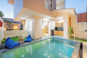 Ett modernt hus med en swimmingpool, ett kök och en matplats.
