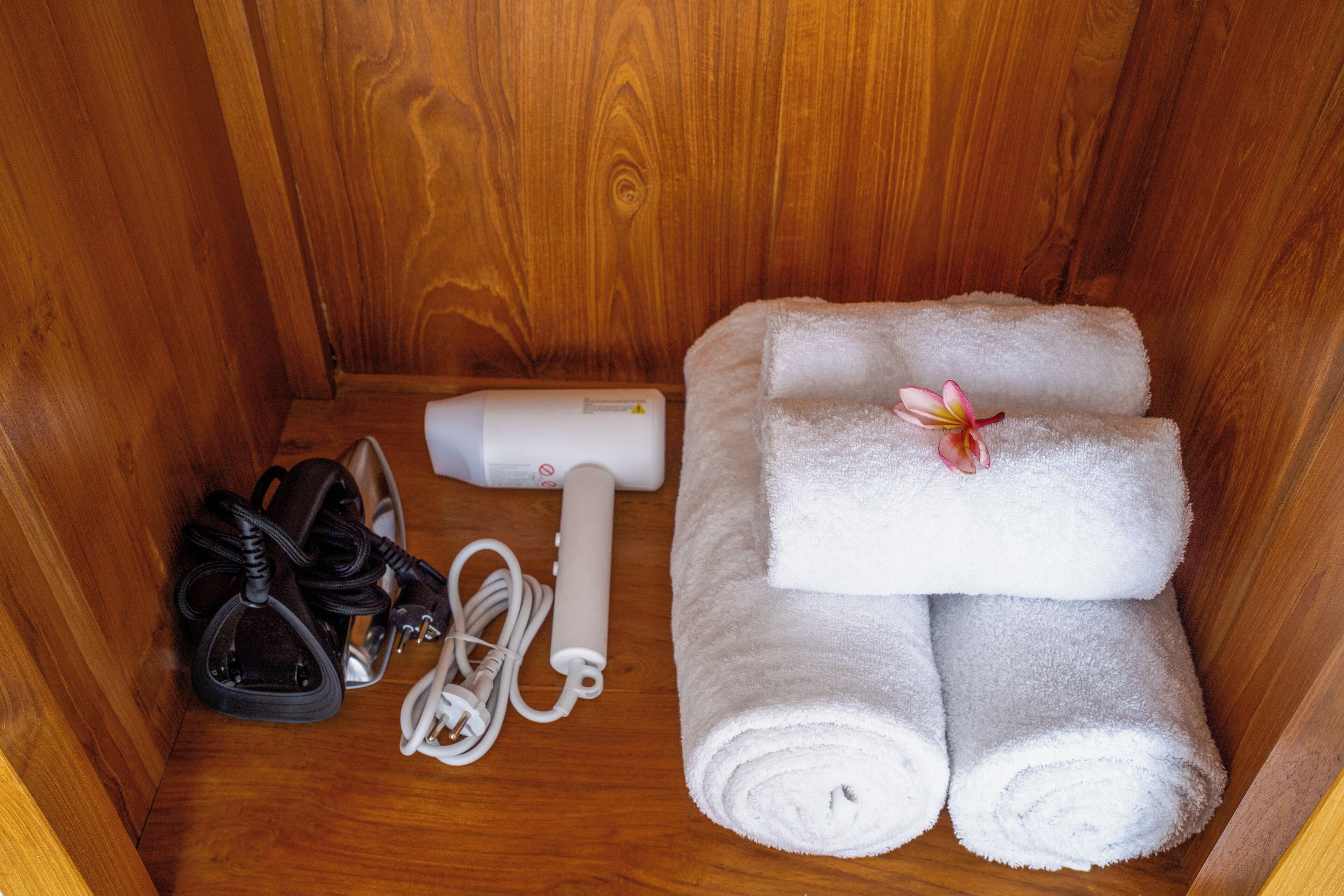 A wooden cabinet with a pair of black shoes, white earphones, and a white portable heater.