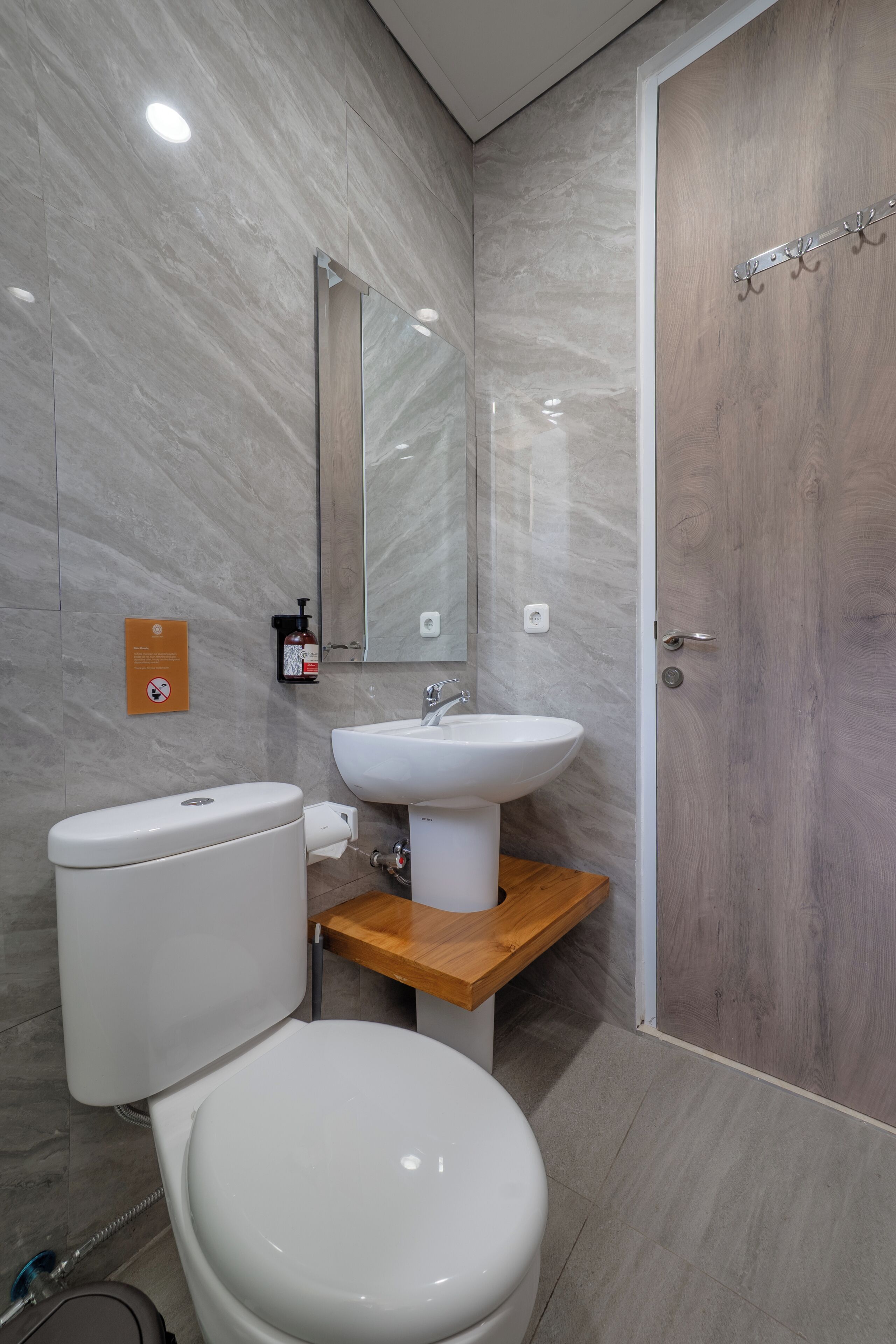 A modern bathroom with a toilet, sink, and wooden vanity.
