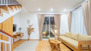 A modern living room with a wooden staircase, a sofa set, a TV, and a dining area with a table and chairs. - Mandala Hill Private Pool Villa Estate Nusa Dua (Nusa Dua)
