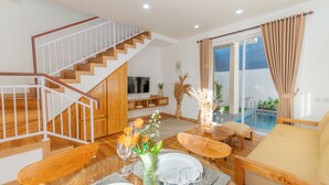 A modern living room with a wooden staircase, a pool area, and a sofa. - Mandala Hill Private Pool Villa Estate Nusa Dua (Nusa Dua)