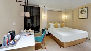 A hotel room with a bed, desk, chair, and bedside table. - The Beacon Hotel NIBM Pune (Pune)