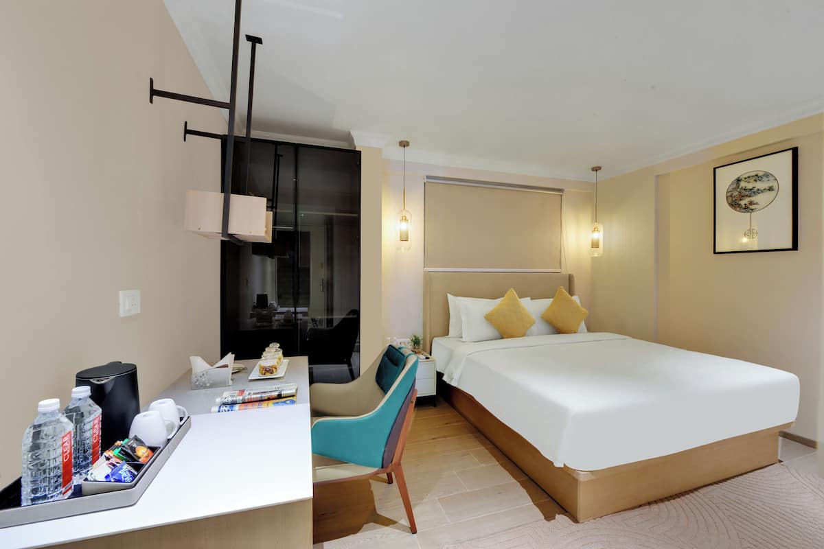 Une chambre d’hôtel équipée d’un lit, d’un bureau, d’une chaise et d’une table de chevet.