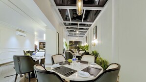 A modern dining area with a round table set for four, surrounded by upholstered chairs. - The Beacon Hotel NIBM Pune (Pune)