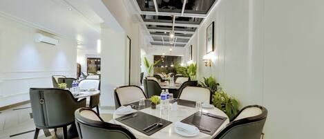 Un espace repas moderne avec une table ronde pour quatre personnes, entourée de chaises rembourrées.