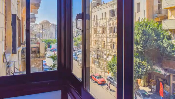 A view from a window overlooking a street with buildings, including a building under construction with scaffolding. - Chic 2-bedroom Apartment in Heliopolis (Cairo Governorate)