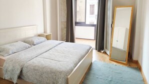 A bedroom with a bed, a bedside table, a mirror, and a view of the outside. - Chic 2-bedroom Apartment in Heliopolis (Cairo Governorate)