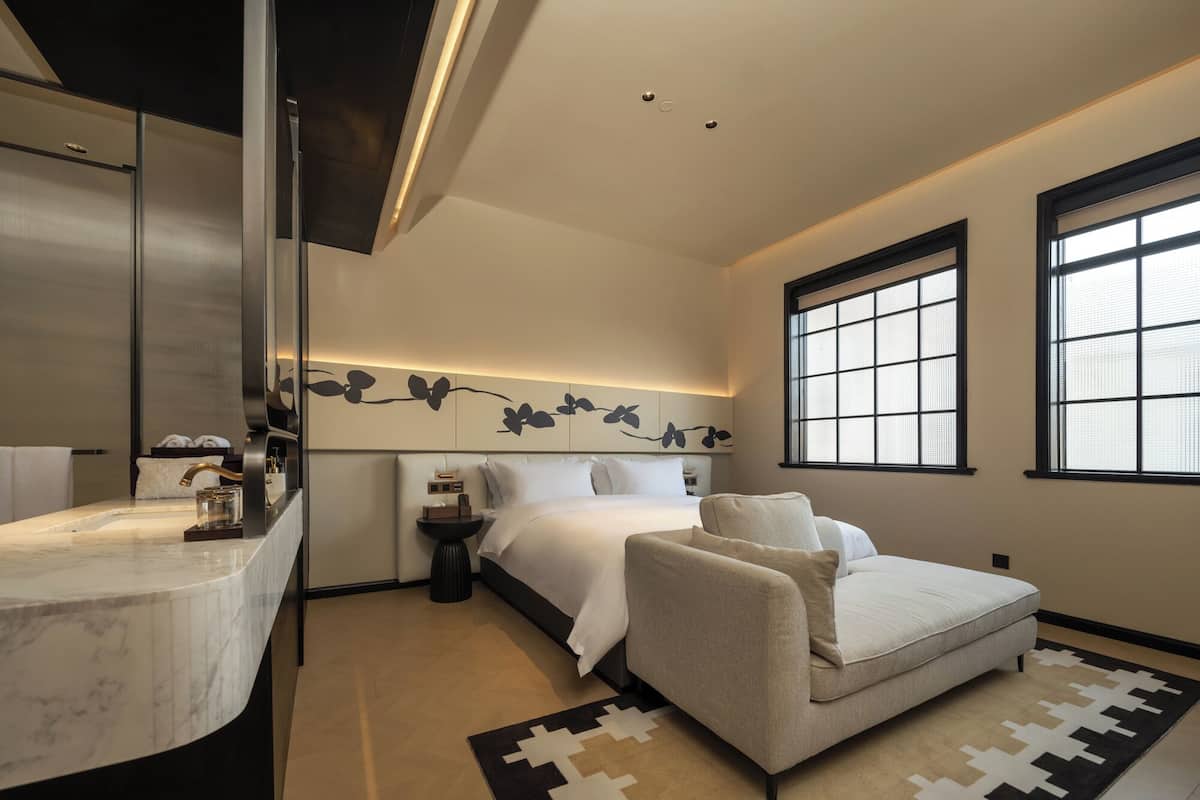 A modern bedroom with a bed, bedside table, and a sofa.