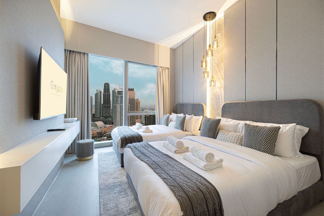 A modern hotel room with a large bed, a TV, and a city view.