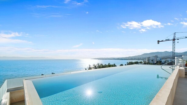 An infinity pool with a clear view of the sea and distant mountains. - Marsala 201: 2BR w/ Rooftop Pool - Walk to Beach (Bucerías)