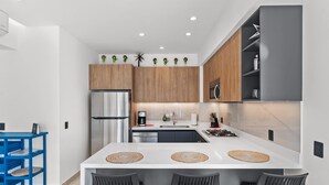 A modern kitchen with a central island, wooden cabinets, and a stainless steel refrigerator. - Marsala 201: 2BR w/ Rooftop Pool - Walk to Beach (Bucerías)