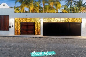 Un bâtiment dont la façade présente un motif géométrique, avec une grande porte en bois et une porte de garage.