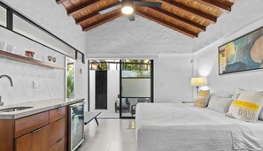 Une chambre à coucher moderne avec un grand lit, une table de chevet, une fenêtre et une vue sur l’extérieur.