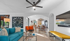 A modern living room with a sofa, coffee table, and a bench. There is a dining area with chairs and a table in the background. - Luxury 6BR in Bucerias Golden Zone: Villa Moderna (Bucerías)