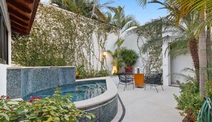 A private outdoor area with a swimming pool, a dining table with chairs, and lush greenery.