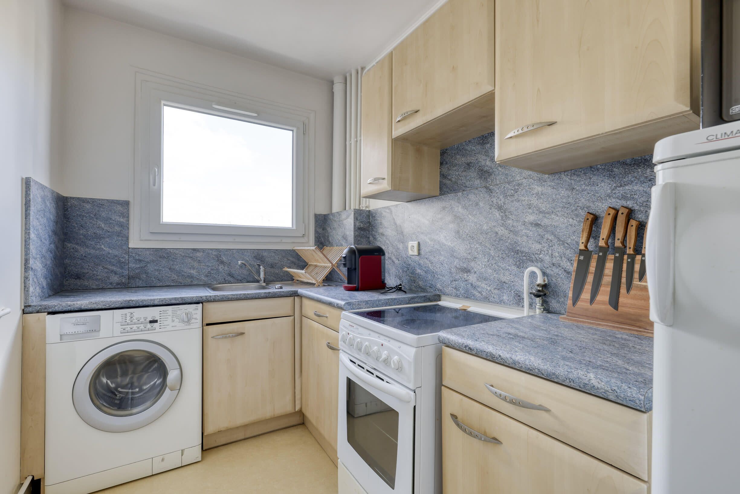 Une cuisine compacte équipée d’un lave-linge, d’une cuisinière et d’un plan de travail.