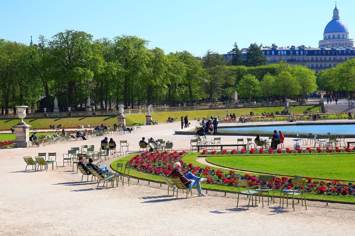 Un parc amb gespa verda, bancs i una font.