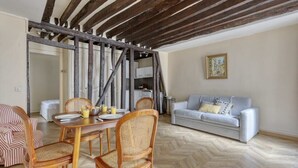 Una zona de menjador amb taula i cadires de fusta, un sofà i un quadre a la paret.