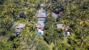 Ein Resort mit mehreren bungalowartigen Gebäuden, einem zentralen Swimmingpool und üppiger tropischer Vegetation.
