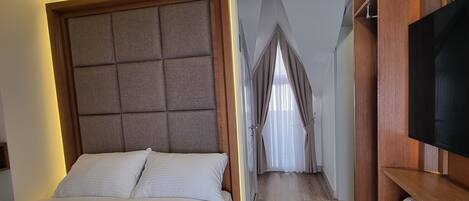 Una habitación de hotel con una cama grande, un televisor y un armario de madera.