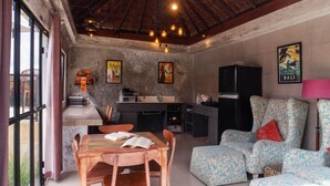 A cozy living area with a dining table, chairs, a sofa, and a kitchen area. - Aurora Holiday House Kintamani (Kintamani)