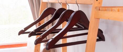 A wooden coat rack with multiple hangers.