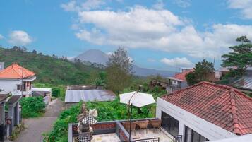 A residential area with houses, a patio with chairs and an umbrella, and a mountain in the background.