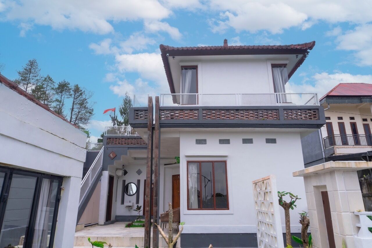 A two-story house with a balcony, a staircase, and a small garden area.