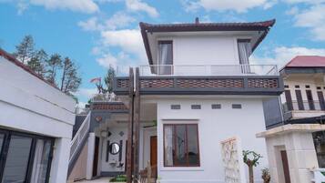 A two-story house with a balcony, a staircase, and a small garden area.